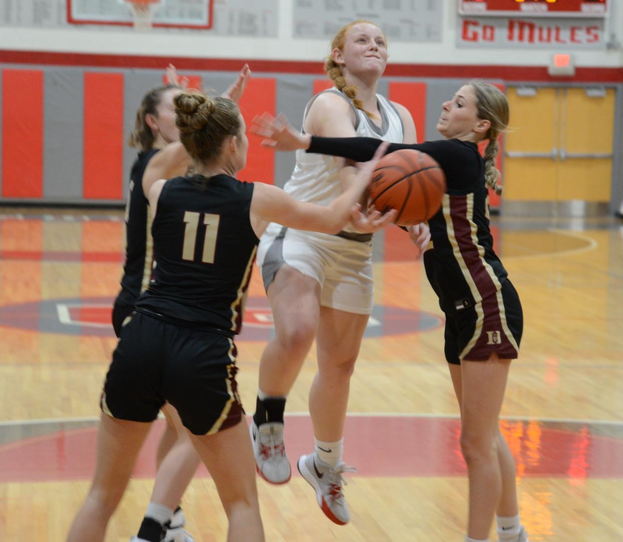 Aubrey Hensley of Bedford is confronted by Addison Chase (11) and Alyssa Gullekson of Bedford on her way to the basket Friday night. The Mules opened their Southeastern Conference season with a 56-37 win over Dexter.