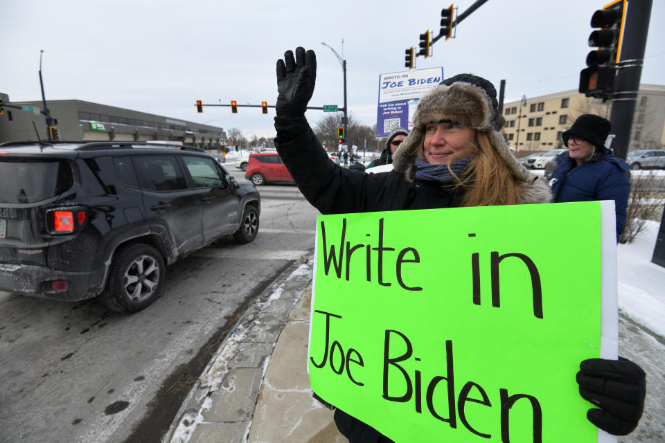 Melissa Hinebauch waves to cars while promoting the write-in campaign to put President Biden’s name on the New Hampshire Democratic primary ballot.