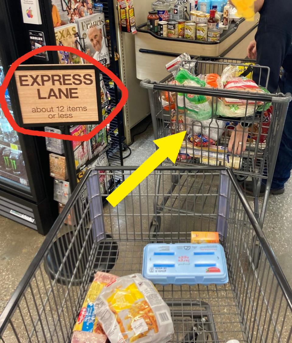 A grocery store express lane with "about 12 items or less" sign. Person checking out with a full cart