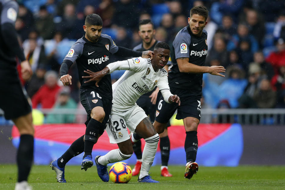 Real Madrid's Vinicius JR, center, battles for the ball with Sevilla's Daniel Carrico, right, and Ever Banega during the La Liga soccer match between Real Madrid and Sevilla at the Bernabeu stadium in Madrid, Spain, Saturday, Jan. 19, 2019. (AP Photo/Andrea Comas)