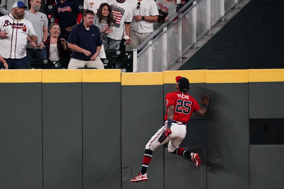 Atlanta Braves center fielder Cristian Pache (25) climbs the center field wall as he chases a ball hit for a two-run home run by Philadelphia Phillies' J.T. Realmuto in the eighth inning of a baseball game Friday, May 7, 2021, in Atlanta. (AP Photo/John Bazemore)