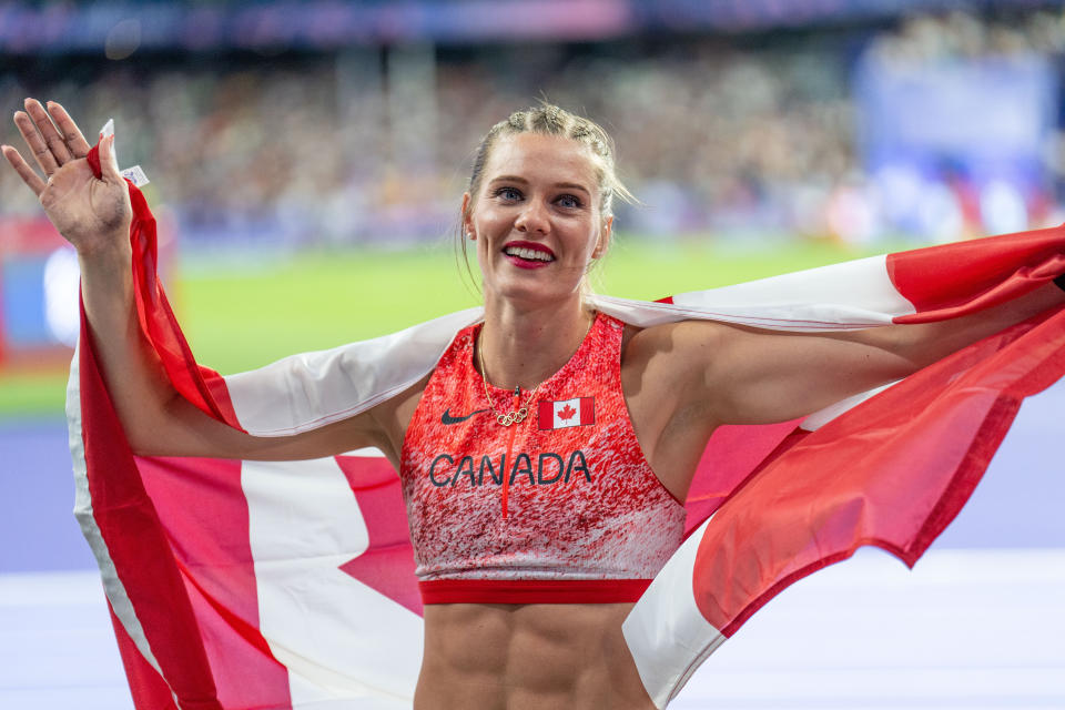 Alysha Newman carries the Canadian flag as she celebrates her bronze medal.