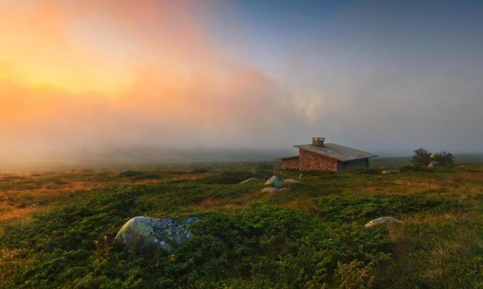 Alpine  landscape with dramatic sky and old stone cabin.