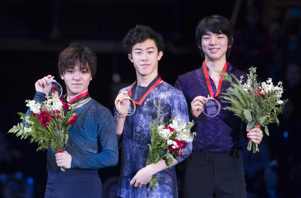 Nathan Chen, of the United States, center, celebrates his gold medal with silver medalist Shoma Uno, of Japan, left, and bronze medalist Jun-hwan Cha, of South Korea, right, following the men's free skate at the figure skating's Grand Prix Final in Vancouver, Friday, Dec. 7, 2018. (Jonathan Hayward/The Canadian Press via AP)