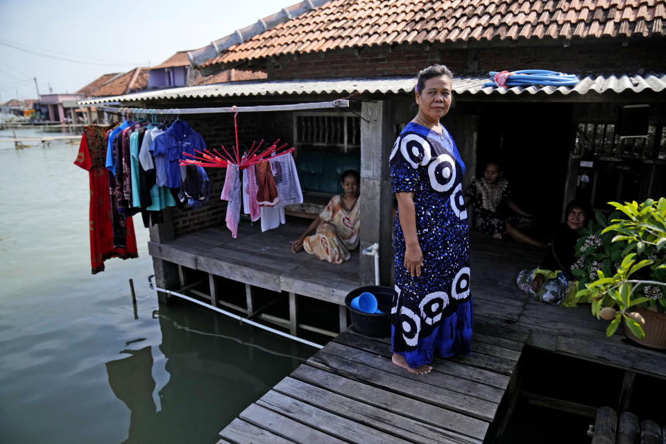 Wahidah stands on her porch with her friends in Timbulsloko, Central Java, Indonesia, Sunday, July 31, 2022. "There's nowhere to go. I think the younger generation should move. If they have money they should buy land. But I don't have money right now, so I stay," she said. (AP Photo/Dita Alangkara)