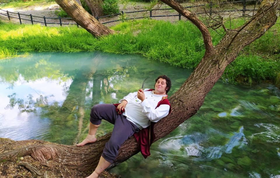 a real life hobbit sitting on a branch above a river