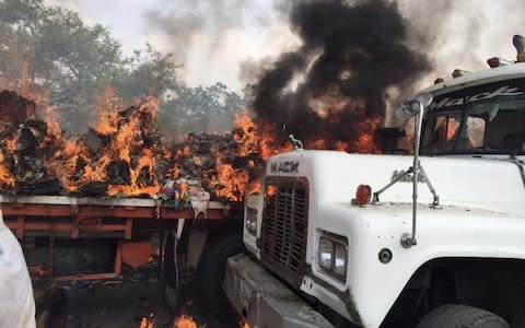 Opposition supporters unload humanitarian aid from a truck that was sent on fire after clashes between opposition supporters and Venezuela's security forces at Francisco de Paula Santander bridge