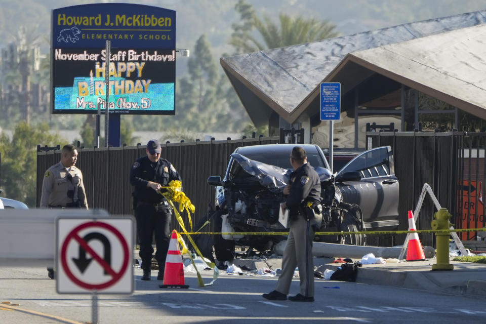 An officer removes police tape around an SUV that struck Los Angeles County sheriff's recruits in Whittier, Calif., Wednesday, Nov. 16, 2022. The vehicle struck several Los Angeles County sheriff's recruits on a training run around dawn Wednesday, some were critically injured, authorities said. (AP Photo/Jae C. Hong)