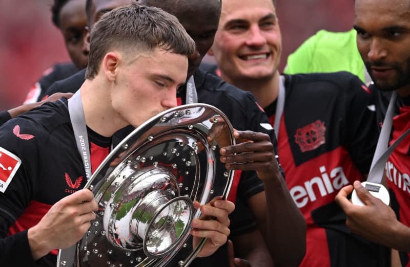 Leverkusen's Florian Wirtz celebrates with the championship trophy following the German Bundesliga soccer match between Bayer Leverkusen and FC Augsburg at BayArena. Marius Becker/dpa