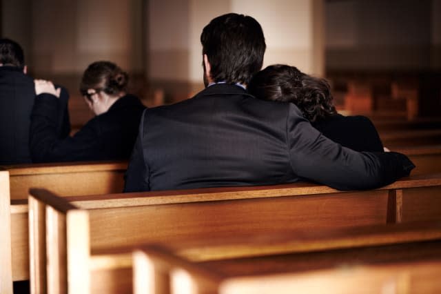 D2G2JW Rearview of a family of mourners sitting in pews at a church funeral service. Image shot 2012. brother; caucasian; ceremo