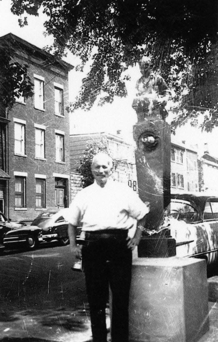 Dominic Conti of Paterson stands in front of the city's Dublin Spring memorial statue outside of his Mill Street grocery store. In 1931, Conti was granted special police privileges to protect the dignity of the statue by the city's fire and police commissions.