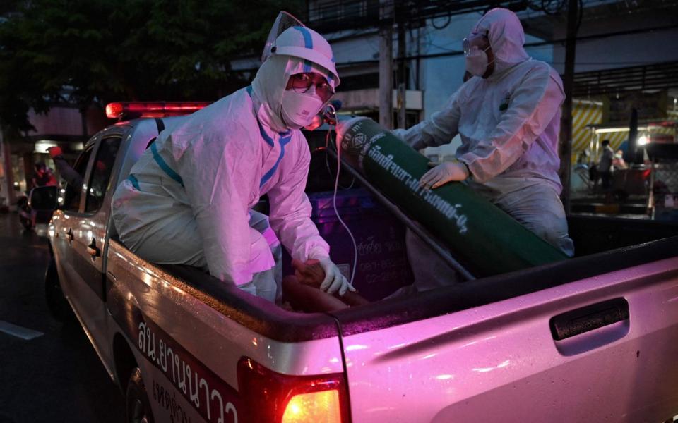 A medic holds the hand of elderly Covid-19 coronavirus patient Worapoj Salee as he is taken away for additional medical care in the Charoen Krung neighbourhood in Bangkok - Lillian SUWANRUMPHA / AFP