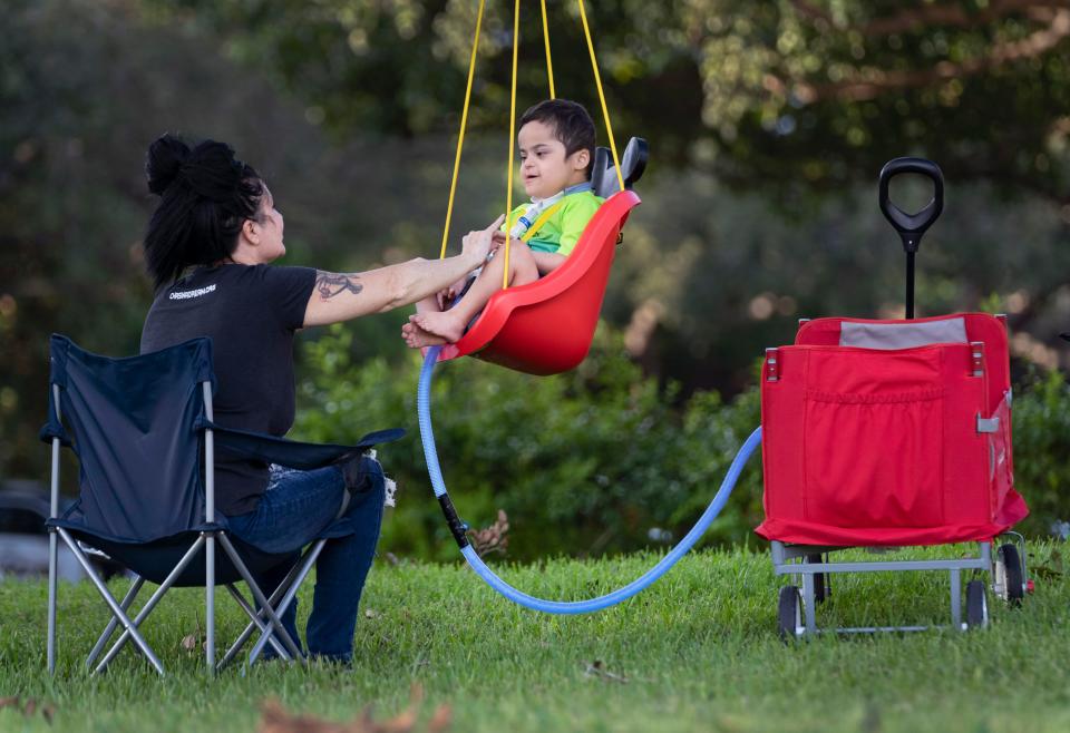 Michelle Thivierge swings her son, Roman Burnette, 5, at outside their home in West Palm Beach, Florida on November 11, 2022. Roman has Downs Syndrome, heart and lung problems.