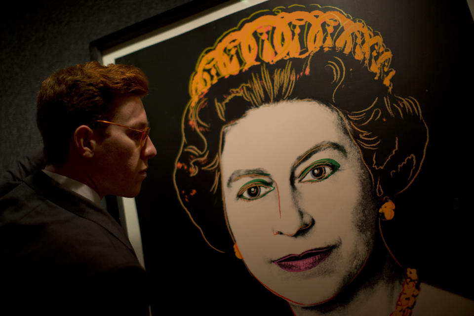 Bonhams employee George Foren poses for photographs with a rare trial proof copy of Andy Warhol's 1985 portrait of Britain's Queen Elizabeth II, at the auction house's offices in central London, July 9, 2012. (AP Photo/Matt Dunham)