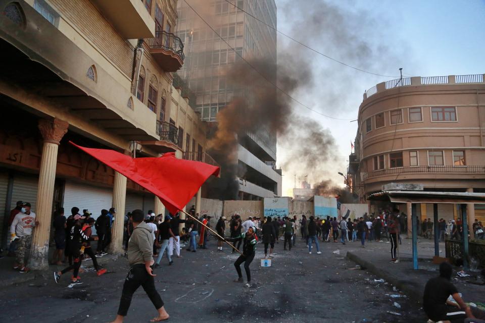 Riot police fire tear gas while protesters set fires during clashes between Iraqi security forces and anti-Government protesters in Baghdad, Iraq, Thursday, Nov. 21, 2019. Iraqi officials said several protesters were killed as heavy clashes erupt in central Baghdad. (AP Photo/Khalid Mohammed)