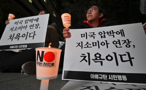 South Korean protesters hold signs that read "It is a disgrace to extend GSOMIA because of the pressure from the US"