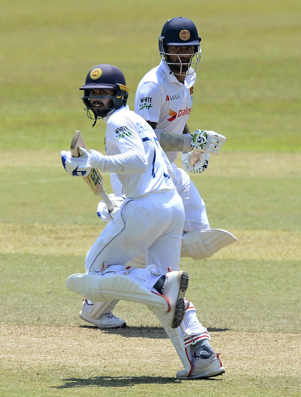 Sri Lankan batsman Dhanajaya De Silva, left, and Dimuth Karunaratna run between wickets during the fourth day of the first test cricket match between Sri Lanka and Bangladesh in Pallekele, Sri Lanka, Saturday, April 24, 2021.( AP Photo/Sameera Peiris)