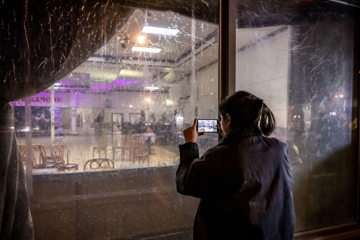 A woman takes cell phone photos through the front window of the Star Ballroom Dance Studio in Monterey Park, Calif., on Sunday. (Photo by Leonard Ortiz/MediaNews Group/Orange County Register via Getty Images)