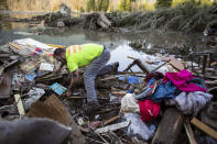 Iraq War veteran and local Little League coach Matt Pater, 32, searches through debris following Saturday's destructive mudslide, near Oso Wash, Monday, March 24, 2014. The search for survivors of Saturday's deadly mudslide grew Monday to include scores of people who were still unaccounted for as the death toll from the wall of trees, rocks and debris that swept through the rural community rose to at least 14. (AP Photo/seattlepi.com, Joshua Trujillo)