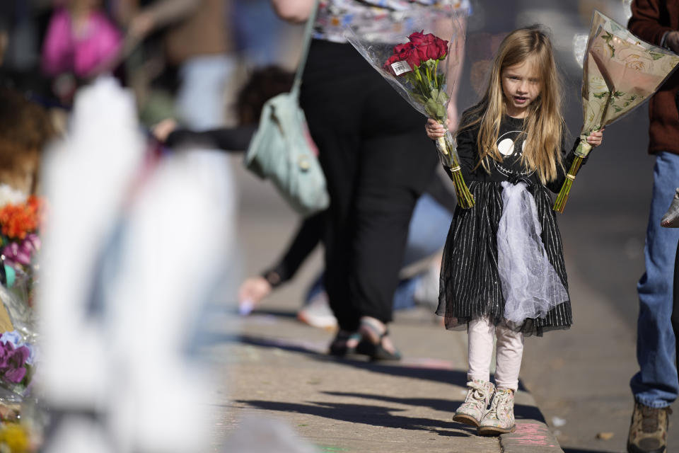 Six-year-old Harper Halvorson carries bouquets of flowers to place a makeshift memorial for victims of a weekend mass shooting at a nearby gay nightclub on Tuesday, Nov. 22, 2022, in Colorado Springs, Colo. Anderson Lee Aldrich opened fire at Club Q, in which five people were killed and others suffered gunshot wounds before patrons tackled and beat the suspect into submission. (AP Photo/David Zalubowski)