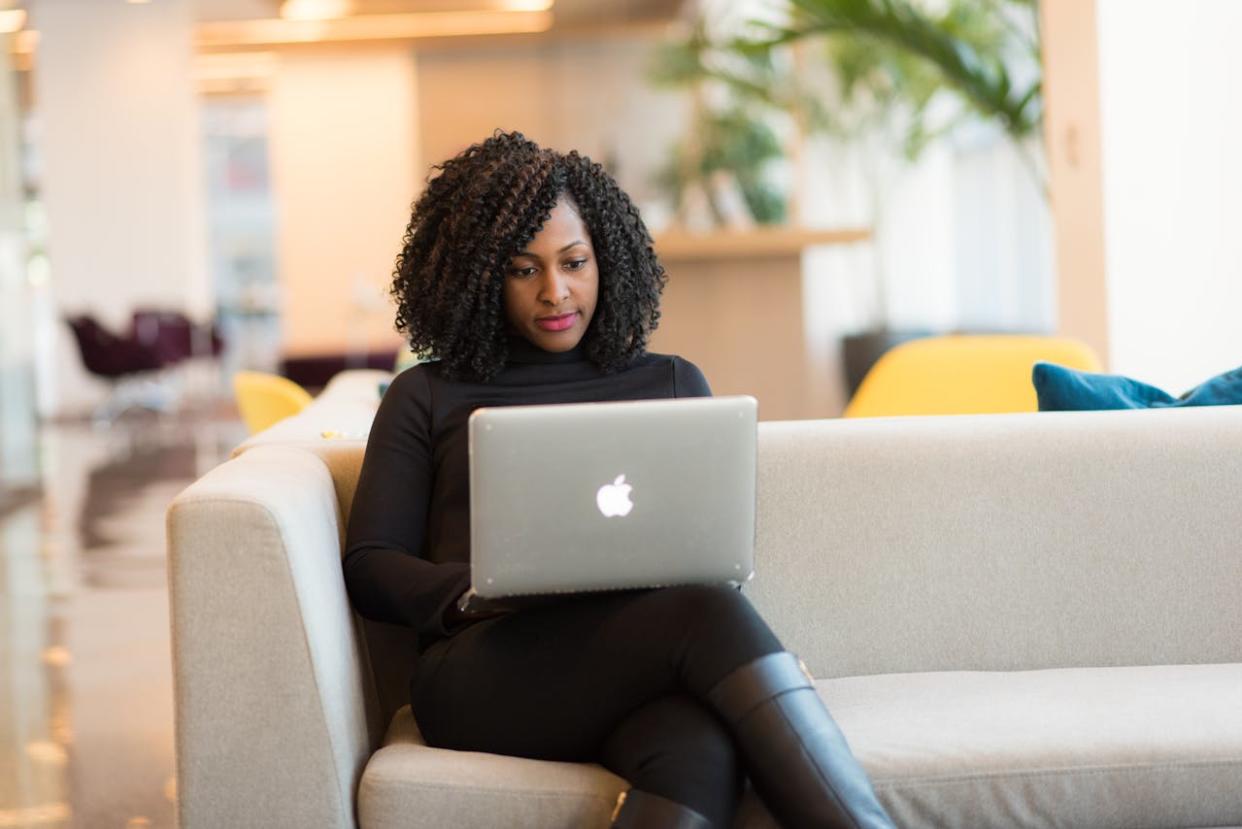 woman sitting on couch looking at google travel apps on laptop