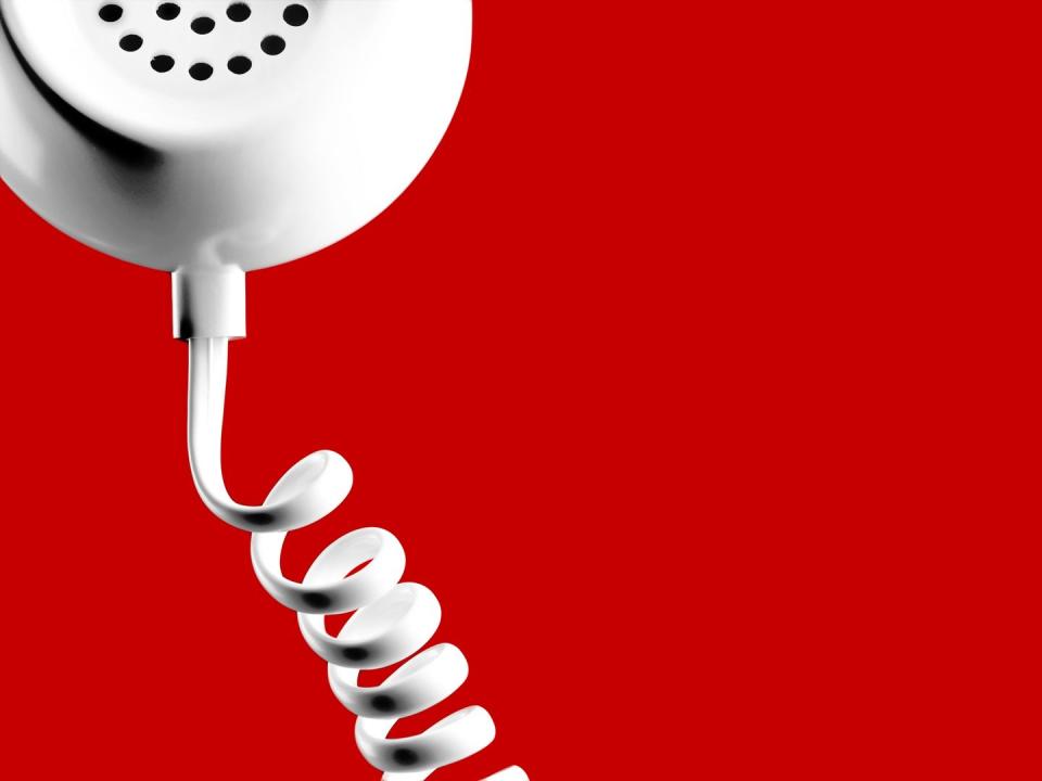 closeup of phone with coil phone chord on red background