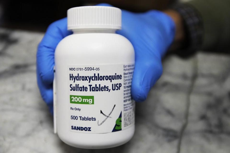 A pharmacist holds a bottle of the drug hydroxychloroquine.