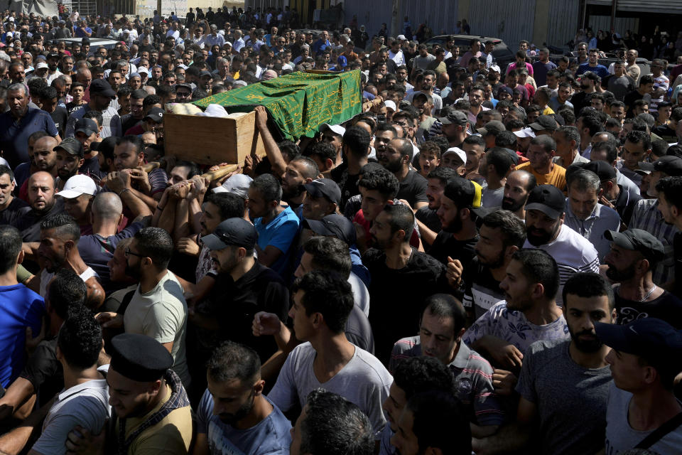 Mourners carry the coffin of Palestinian Abdul-Al Omar Abdul-Al, 24, who was on a boat carrying migrants from Lebanon that sank in Syrian waters, during his funeral processions, in the Palestinian refugee camp of Nahr el-Bared near the northern city of Tripoli, Lebanon, Saturday, Sept. 24, 2022. Thousands of Palestinians held prayers in northern Lebanon Saturday for one of the scores of migrants who lost their lives this week when their boat sank off Syria's coast. (AP Photo/Bilal Hussein)