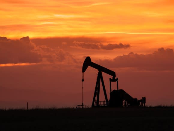 An oil pump with an orange sky in the background.