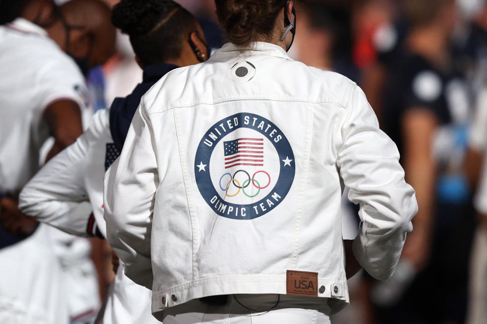 A person wearing a white jacket with the "United States Olympic Team" logo on the back. The logo includes the American flag and Olympic rings