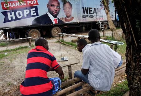 Supporters of George Weah, former soccer player and presidential candidate of Congress for Democratic Change (CDC), listen to the announcement of the presidential election results on the radio, in Monrovia, Liberia October 15, 2017. REUTERS/Thierry Gouegnon