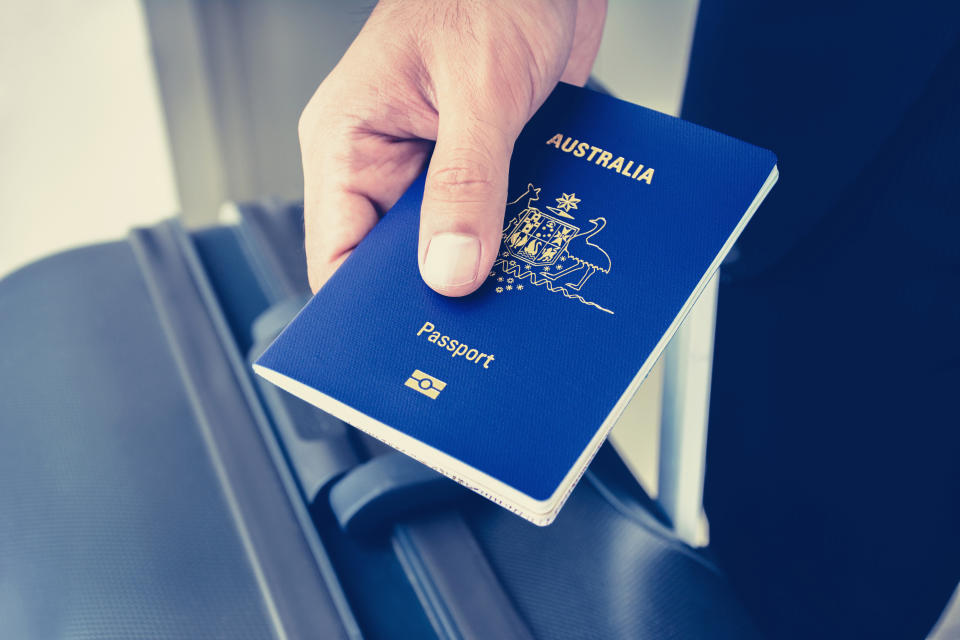 Hands giving passport of Australia to electronic reader