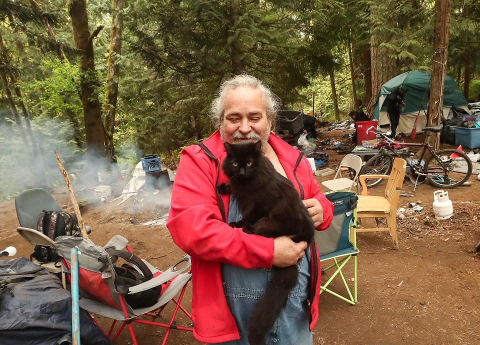 Chris Field holds his cat, Midnight, as he and friends break down their campsites at Veterans Memorial Park in Port Orchard on Friday.