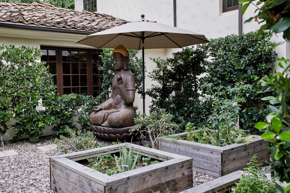 One of the outdoor patios has an imported Thai Buddha statue and raised beds filled with vegetables.