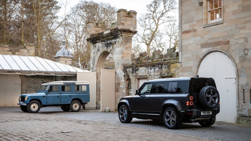 A photo of two Land Rover Defender 110s in the grounds of a large house. 