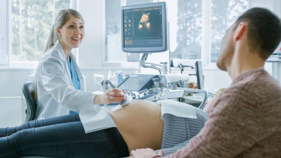 In the Hospital, Pregnant Woman Getting Ultrasound / Sonogram Scan, Obstetrician Explains Procedure to Her and Her Supportive Husband.