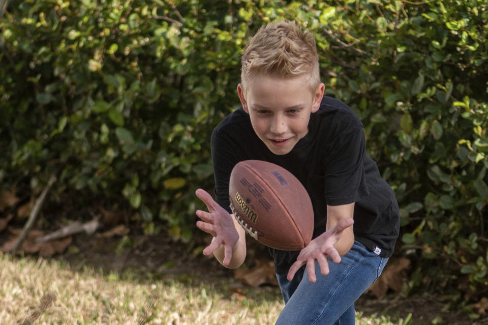 Colton Nover, 10, plays football with his younger brother on their front lawn Wednesday, Feb. 16, 2022, in St. Johns, Fla. Colton has an issue with stuttering as does his mother. Stuttering has been documented as far back as ancient China, Greece and Rome. But no one really had any idea what caused it until modern genetic science and brain imaging began providing clues. (AP Photo/Fran Ruchalski)