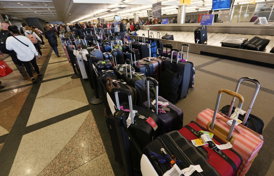 Travelers pass by hundreds of pieces of unclaimed luggage in Denver International Airport after a winter storm swept over the country packing snow combined with Arctic cold, which created chaos for people trying to reach their destinations before the Christmas holiday, Friday, Dec. 23, 2022, in Denver. Forecasters predict that warmer weather will be on tap for the week ahead. (AP Photo/David Zalubowski)