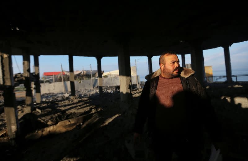 Palestinian man inspects a destroyed wedding hall after being attacked by Israeli aircrafts, in Gaza