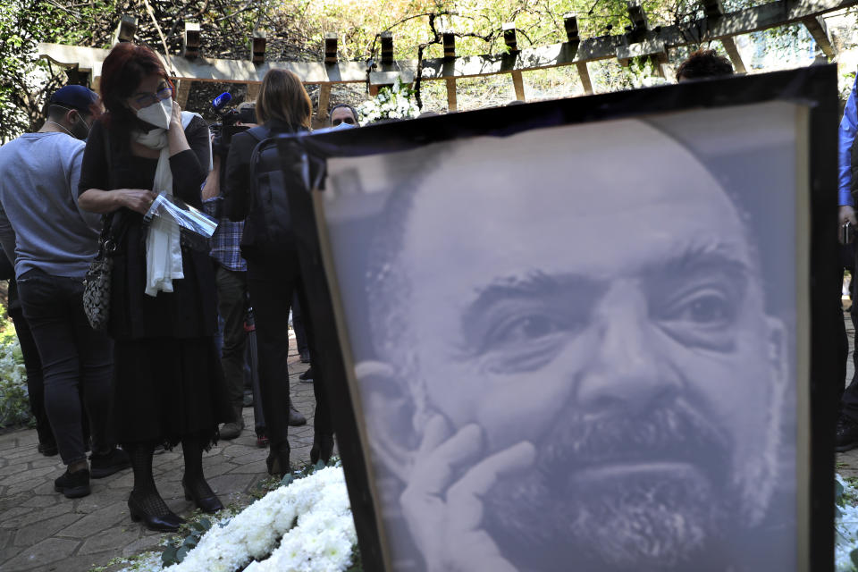 A mourner, left, looks at a monument of Lokman Slim during a memorial service to pay tribute to the slain Lebanese publisher and vocal critic of Hezbollah group in the southern suburb of Beirut, Lebanon, Thursday, Feb. 11, 2021. Scores of friends and family members bid Slim farewell Thursday in a ceremony attended by western diplomats and organized in his home in the southern suburb of Beirut amid tight security. (AP Photo/Hussein Malla)