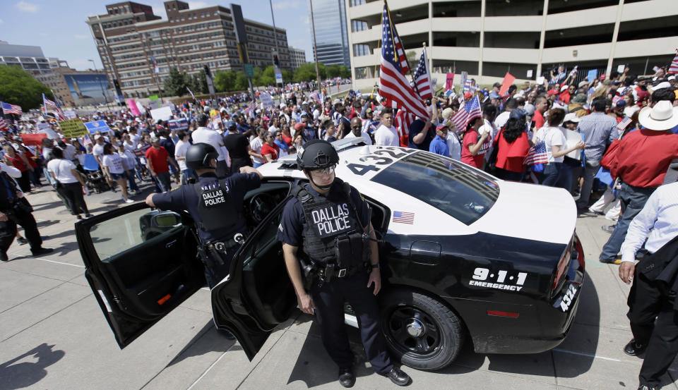 Dallas police stand guard during a protest march through downtown Dallas, Sunday, April 9, 2017. Thousands of people are marching and rallying in downtown Dallas to call for an overhaul of the nation's immigration system and end to what organizers say is an aggressive deportation policy. (AP Photo/LM Otero)