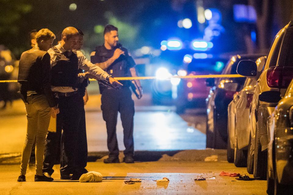 In this Thursday, June 14, 2018 photo, Chicago Police officers investigate the scene where two people were shot in Chicago. A 12-year-old Michigan girl spending the summer in Chicago was fatally shot at the scene, hours after attending a cousin's eighth-grade graduation. Family members at the hospital identified the girl as She'nyah O'Flynn of Covert, Michigan. She and a man who was injured were apparently unintended victims of gunfire from a nearby party. Police say there have been no arrests.