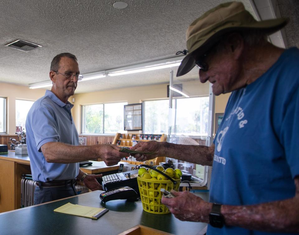 Lone Pine Golf Club co-owner Richard Gerlach accepts payment from customer Norman Greene, 82, for a basket of driving range golf balls at Lone Pine Golf Club in Riviera Beach on June 23, 2022.