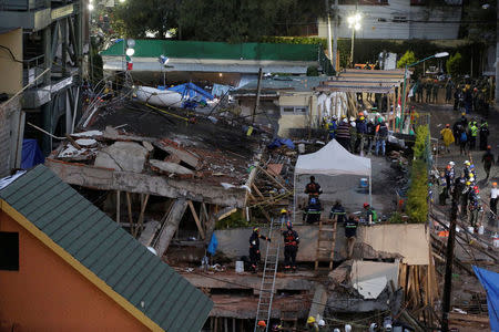 Rescue workers and volunteers are seen next to parts of a collapsed school building during a search for students at the Enrique Rebsamen school after an earthquake in Mexico City, Mexico September 21, 2017. REUTERS/Jose Luis Gonzalez