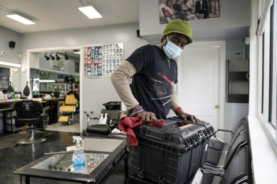 A worker at the popular Top Class Barber Shop in Falls Church, Va., a suburb of Washington, cleans surfaces in preparation for a possible reopening after weeks of forced closure during the COVID-19 pandemic, Monday, May 11, 2020. The Northern Virginia suburbs of Washington are a significant part of the state's economy, but the region's top elected officials are objecting to Gov. Ralph Northam's plan to begin lifting shutdown restrictions there because of the lingering coronavirus health emergency. (AP Photo/J. Scott Applewhite)