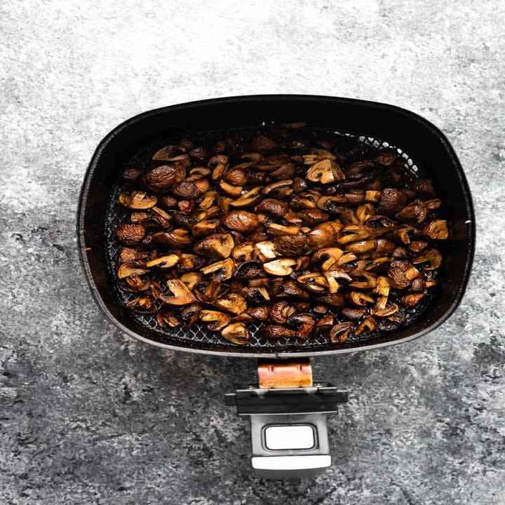 Mushrooms in the basket of an air fryer.