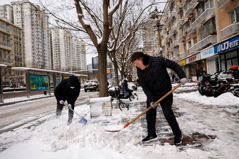 Trabajadores retiran la nieve de una calle peatonal tras una nevada en Pekín