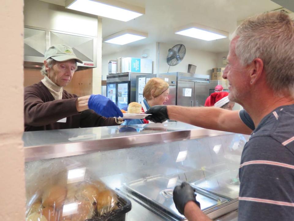 Jim Tinnin, left, handed plates full of hot food to other volunteers at the Salvation Army at the annual Christmas Day meal. Attendees were seated and served by volunteers, restaurant-style, at the free meal.