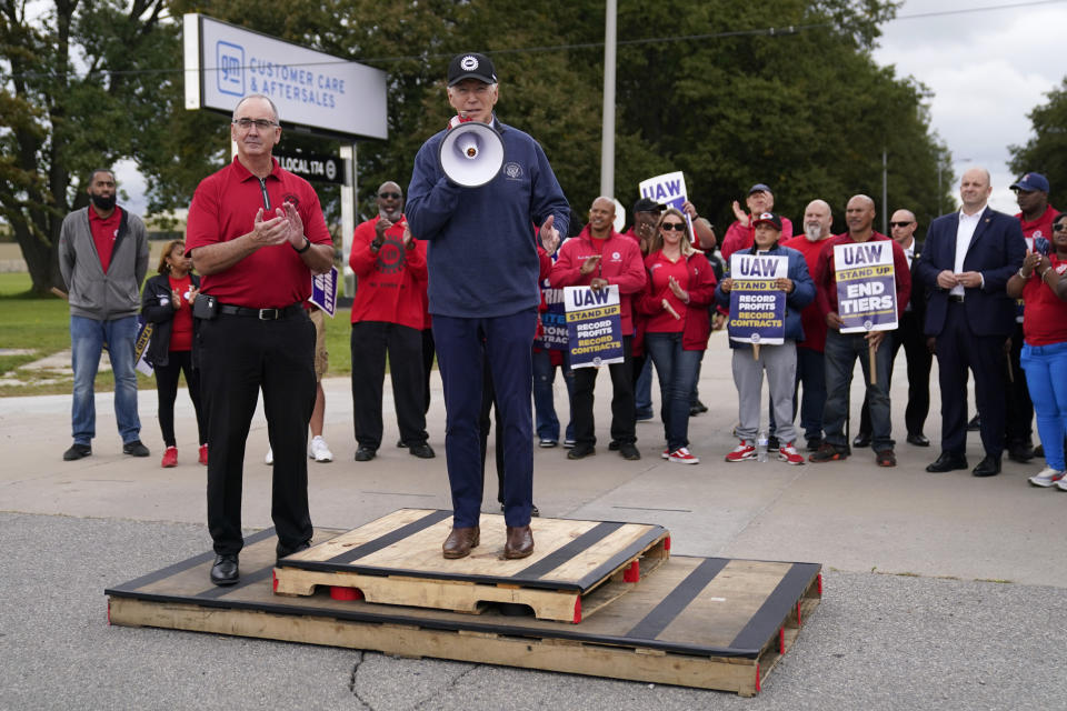 FILE - President Joe Biden joins striking United Auto Workers on the picket line as UAW President Shawn Fain listens at left, Sept. 26, 2023, in Van Buren Township, Mich. Biden will be the keynote speaker Wednesday, Jan. 24, at a UAW political convention as he works to sway blue-collar workers his way in critical auto-making swing states such as Michigan and Wisconsin. (AP Photo/Evan Vucci, File)