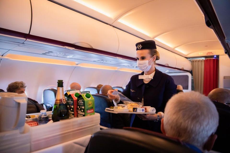 An Air France flight attendant serves drinks on a plane